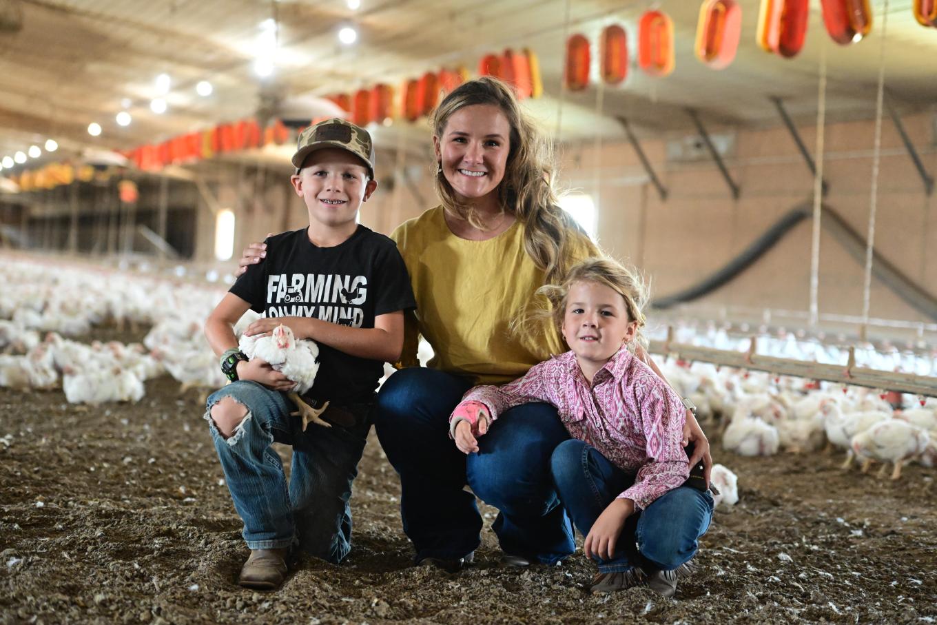 family in chicken coop raising chicken